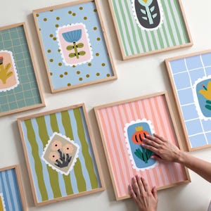 Puede incluir: Una colecci&oacute;n de l&aacute;minas art&iacute;sticas enmarcadas con dise&ntilde;os florales. Cada l&aacute;mina presenta una colorida ilustraci&oacute;n floral dentro de un borde similar a un sello postal. Los fondos var&iacute;an con patrones como rayas, puntos y cuadr&iacute;culas. Los marcos son de madera clara.