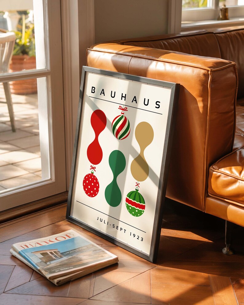 May include: A framed Bauhaus poster with a cream background featuring the text BAUHAUS at the top and JULI-SEPT 1923 at the bottom. The design includes three vertical columns of abstract shapes and Christmas ornaments in red, green, and gold.