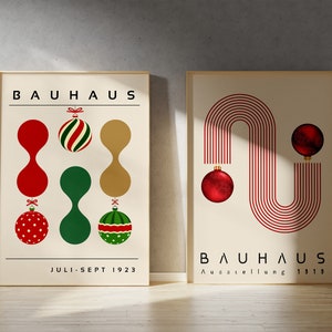 May include: Two framed posters with cream backgrounds. The left poster features the text BAUHAUS and JULI-SEPT 1923 with red, green, and gold ornaments. The right poster features the text BAUHAUS and Ausstellung 1919 with red lines and ornaments.