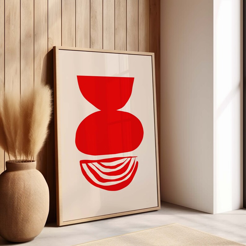 May include: A framed abstract art print with a red geometric design on a cream background. The design features three overlapping circles, with the bottom circle having a striped pattern.