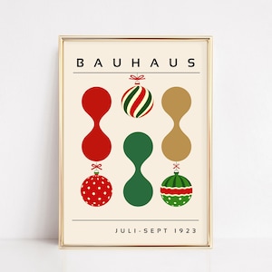 May include: A framed poster with a cream background featuring the text BAUHAUS at the top and JULI-SEPT 1923 at the bottom. The design includes three vertical columns of abstract shapes and Christmas ornaments in red, green, and gold colors.