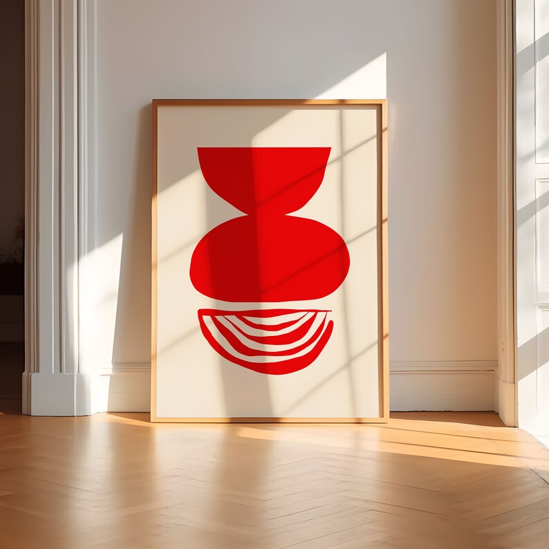 May include: A framed print with a red abstract design of three overlapping shapes. The shapes are a bowl, a circle, and a half-circle.
