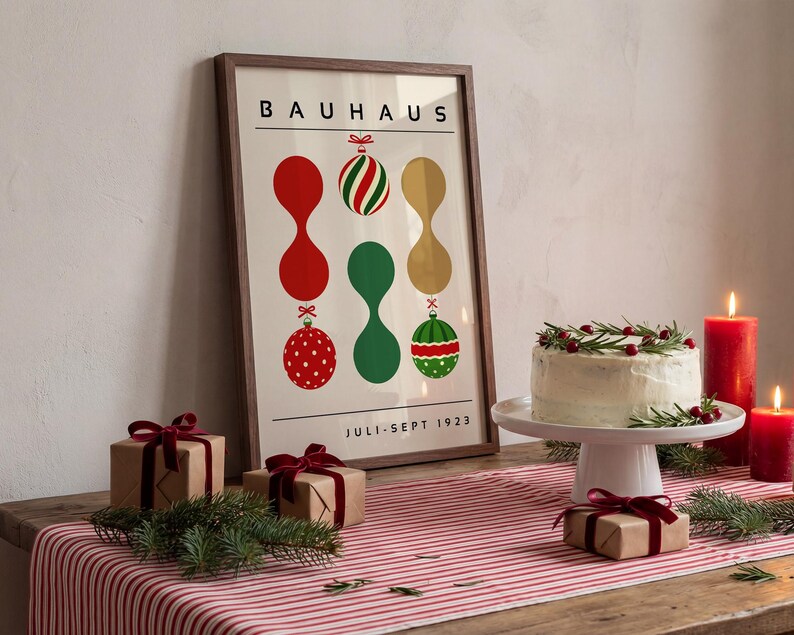 May include: A framed poster with the text BAUHAUS and JULI-SEPT 1923, featuring a graphic design of red, green, and gold abstract shapes and Christmas ornaments. The poster is displayed alongside a frosted cake and wrapped gift boxes.