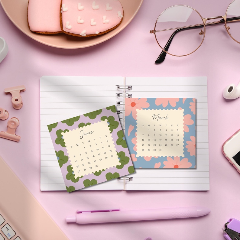 May include: A spiral-bound notebook featuring two square calendar pages for June and March. The June page has a green clover pattern, while the March page displays a blue background with pink flowers. Both pages have scalloped edges.