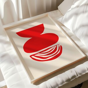 May include: A framed abstract art print with a red, white, and cream color scheme. The print features three overlapping geometric shapes in a vase-like arrangement.
