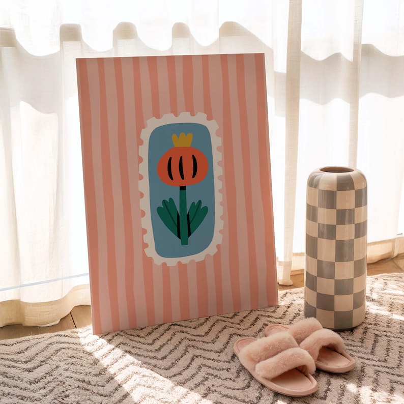 Puede incluir: Una impresi&oacute;n art&iacute;stica decorativa con un fondo a rayas rosas y blancas. La impresi&oacute;n presenta un dise&ntilde;o floral dentro de una forma azul similar a un sello. Tambi&eacute;n se ven un jarr&oacute;n a cuadros y zapatillas rosas.