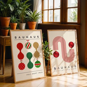 May include: Two framed posters with light backgrounds and wooden frames. The left poster features the text BAUHAUS, JULI-SEPT 1923, and abstract shapes with Christmas ornaments. The right poster displays BAUHAUS, Ausstellung 1923, and red line art.