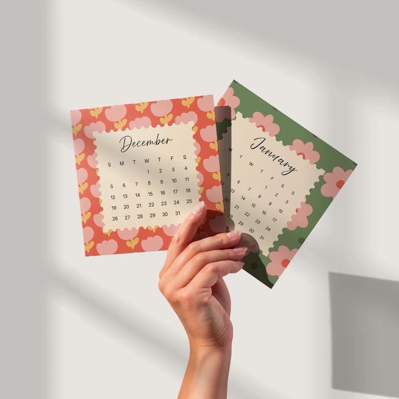 May include: Two square calendar cards featuring the months of December and January. The December card has a red background with pink flower patterns, while the January card has a green background with pink flowers. Both display black text.