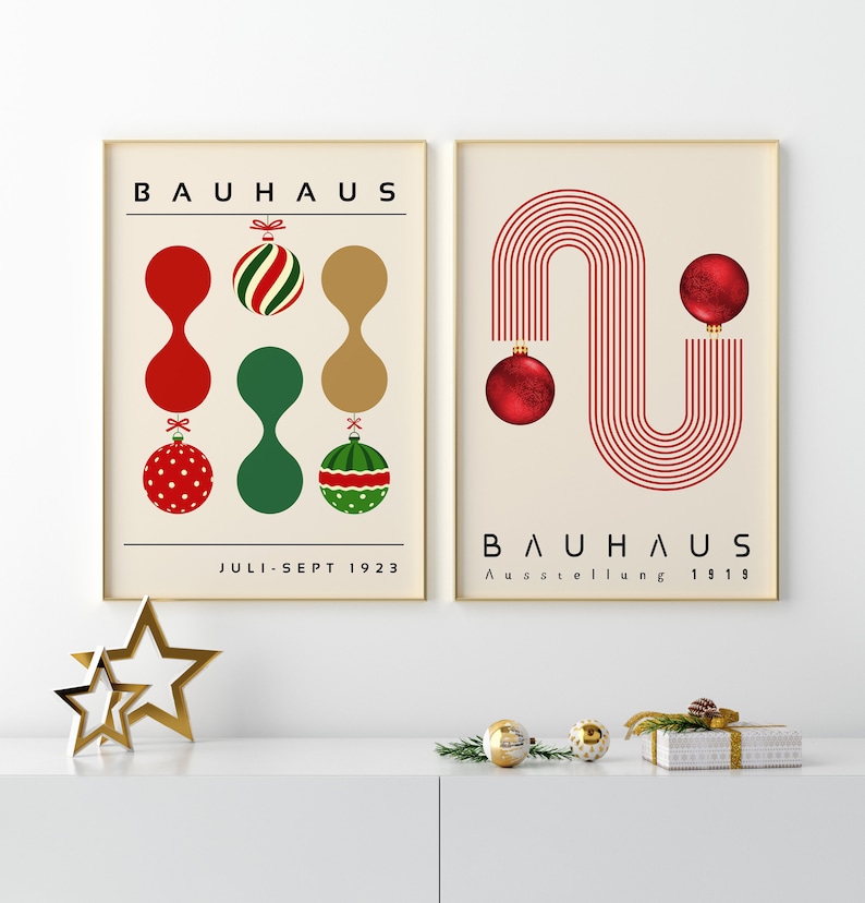 May include: Two framed posters with cream backgrounds. The left poster features the text BAUHAUS and JULI-SEPT 1923 with red, green, and gold abstract shapes and Christmas ornaments. The right poster features BAUHAUS AUSSTELLUNG 1919 with red lines and ornaments.