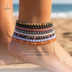 May include: A stack of gemstone anklets in various colors, including brown, green, pink, silver, white, and orange. The anklets are made of small, round beads. The text "DELICATE GEMSTONE STACKING ANKLET SET" is visible.