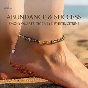 May include: Ankle bracelet with smoky quartz, tiger eye, pyrite, and citrine beads. The gold-colored chain features a small heart charm. Text on the image reads "ABUNDANCE & SUCCESS".