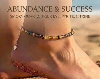 May include: Ankle bracelet with smoky quartz, tiger eye, pyrite, and citrine beads. The gold-colored chain features a small heart charm. Text on the image reads "ABUNDANCE & SUCCESS".