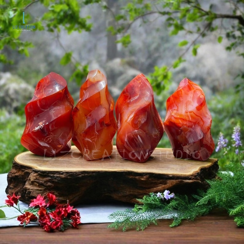 May include: Four red carnelian crystal flame shaped stones on a wooden base. The stones are a deep red color with white and orange swirls.
