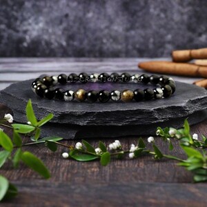 Op de afbeelding: Zwarte, gouden en zilveren kralen armband. De armband is gemaakt met zwarte onyx, hematiet en gouden pyriet kralen.