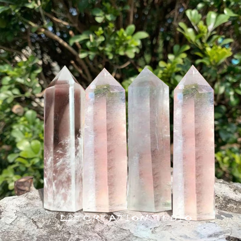 Puede incluir: Cuatro puntas de cristal transparentes con colores arco&iacute;ris iridiscentes. Las puntas est&aacute;n dispuestas en una fila sobre una superficie de piedra gris.