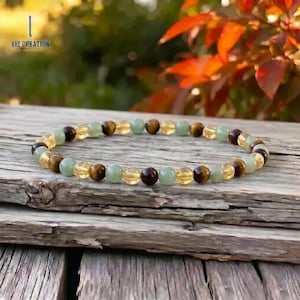 May include: A beaded bracelet featuring a mix of gemstones. The bracelet includes round beads in shades of yellow, brown, and green. The bracelet is displayed on a weathered wooden surface. The text "LIZ CREATION" is visible in the upper left corner.