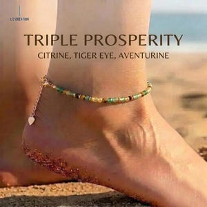 Puede incluir: Pulsera de tobillo con cuentas de citrino, ojo de tigre y aventurina. La cadena dorada tiene un dije de corazón. El texto de la imagen dice "TRIPLE PROSPERITY" y "CITRINE, TIGER EYE, AVENTURINE".