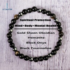 Op de afbeelding: Zwarte armband met kralen van goudglans-obsidiaan, hematiet, zwarte onyx en zwarte toermalijn. De armband ligt op een houten oppervlak en heeft de tekst "Spiritual Protection Mind+Body+Mental Health" erop.
