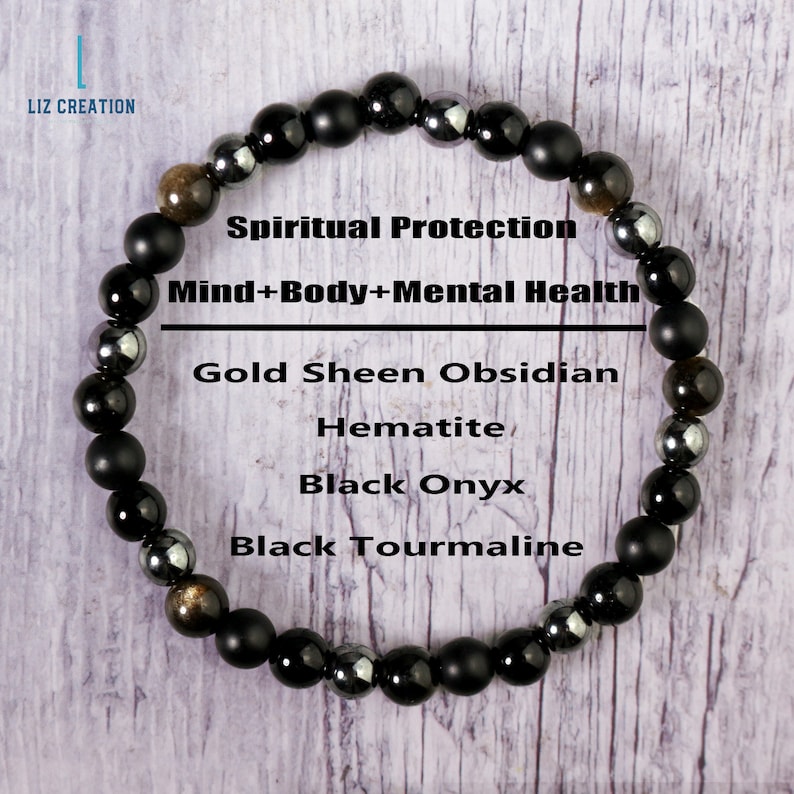 Op de afbeelding: Zwarte armband met kralen van goudglans-obsidiaan, hematiet, zwarte onyx en zwarte toermalijn. De armband ligt op een houten oppervlak en heeft de tekst "Spiritual Protection Mind+Body+Mental Health" erop.