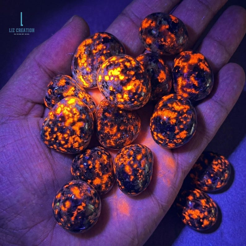 Puede incluir: Colecci&oacute;n de piedras pulidas con un llamativo patr&oacute;n naranja y negro, sostenidas en una mano. Las piedras tienen un aspecto brillante, con el texto "LIZ CREATION" en la esquina superior izquierda.