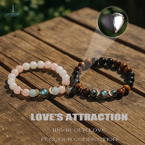 May include: Two beaded bracelets with a heart-shaped charm. One bracelet features pink and white beads, the other has brown, black, and gold beads. The bracelets are on a wooden surface. Text reads "LOVE'S ATTRACTION, WEAR OUR LOVE, FEEL OUR CONNECTION."