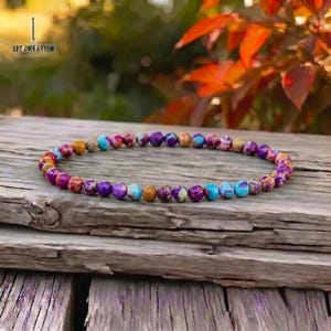 May include: A multi-coloured beaded bracelet with purple, blue, orange, and red gemstones. The bracelet is displayed on a weathered wooden surface. The text "LIZ CREATION" is visible in the upper left corner. The bracelet is a stylish accessory.