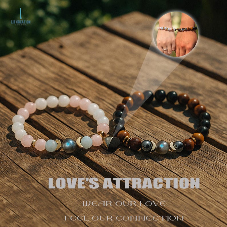 Pode incluir: Duas pulseiras de contas, uma com contas rosa e brancas, a outra com contas castanhas e pretas. As pulseiras est&atilde;o sobre uma superf&iacute;cie de madeira. O texto "LOVE'S ATTRACTION" &eacute; vis&iacute;vel.