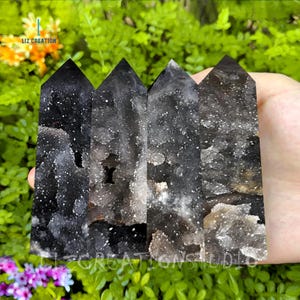 May include: Four black and white crystal points with a cloudy, translucent appearance. The points are arranged in a row and are approximately 7.5 cm tall.