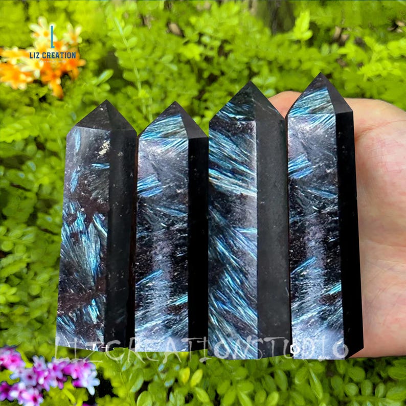 May include: Four black and blue iridescent crystal points, also known as spectrolite, arranged in a row. The points are smooth and polished, with a dark blue and black color that shimmers with iridescent hues.