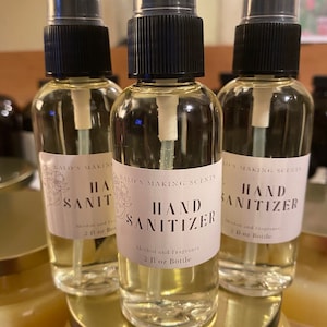 May include: Three clear glass bottles with black spray tops and white labels. The labels read "Kalo's Making Scents Hand Sanitizer Alcohol and Fragrance 2 fl oz Bottle".