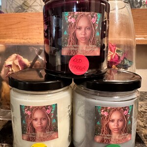 May include: Three glass jars with black lids containing candles. Each jar has a label with a woman's portrait and text. The labels read "Red Sangria", "Sweet Love", and "Him".