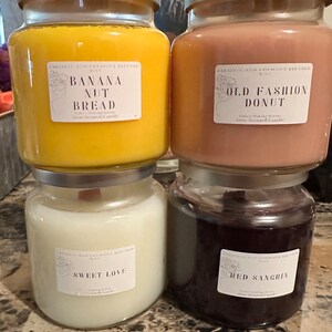 May include: Four glass jars with lids containing scented candles. The candles are labeled "Banana Nut Bread", "Old Fashion Donut", "Sweet Love", and "Red Sangria".