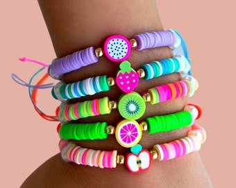 May include: A stack of colorful bracelets with fruit charms. The bracelets are made of small, round beads in various colors, including pink, green, yellow, and blue. Each bracelet has a different fruit charm, including a watermelon, strawberry, kiwi, orange, and apple.