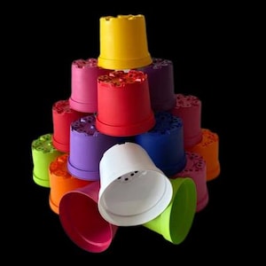 May include: A stack of colourful plastic flower pots with drainage holes. The pots are in various colours, including red, yellow, blue, green, purple and white.