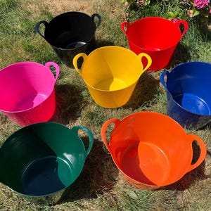 May include: A collection of six flexible plastic tubs, each featuring two integrated handles. The set includes one black, one red, one yellow, one pink, one blue, one green, and one orange tub, all arranged in a group on a grassy surface.
