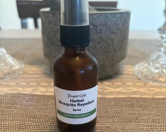 May include: A brown glass bottle with a black spray top and a white label that reads "Foragers Gold Herbal Mosquito Repellent Spray Lemon & Eucalyptus".