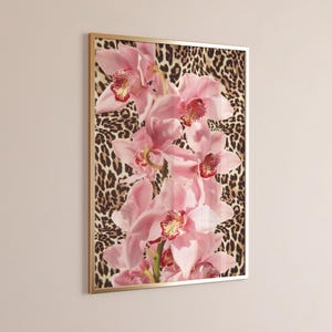May include: A framed print featuring pink orchids on a leopard print background. The orchids are arranged vertically and the print has a gold frame.