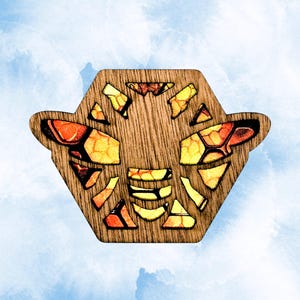May include: A wooden bee-shaped ornament featuring a hexagonal outline and intricate cutouts. The design incorporates vibrant yellow, orange, and red mosaic-style patterns within the wings and body segments, contrasting against the natural wood grain.