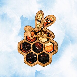 May include: Wooden bee-shaped brooch with a honeycomb design. The bee's wings and body feature intricate details in shades of orange, brown, and yellow. The honeycomb cells are filled with various colors, creating a unique and eye-catching accessory.
