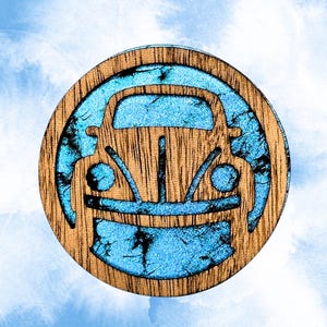 May include: A circular wooden ornament featuring a cutout silhouette of a classic car. The design is inlaid with a textured, bright blue material that fills the negative space around the car shape, creating a contrast between the wood and blue.