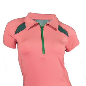 Pode incluir: Uma camisa rosa de manga curta com um z&iacute;per verde e pain&eacute;is de malha verde escura nos ombros.