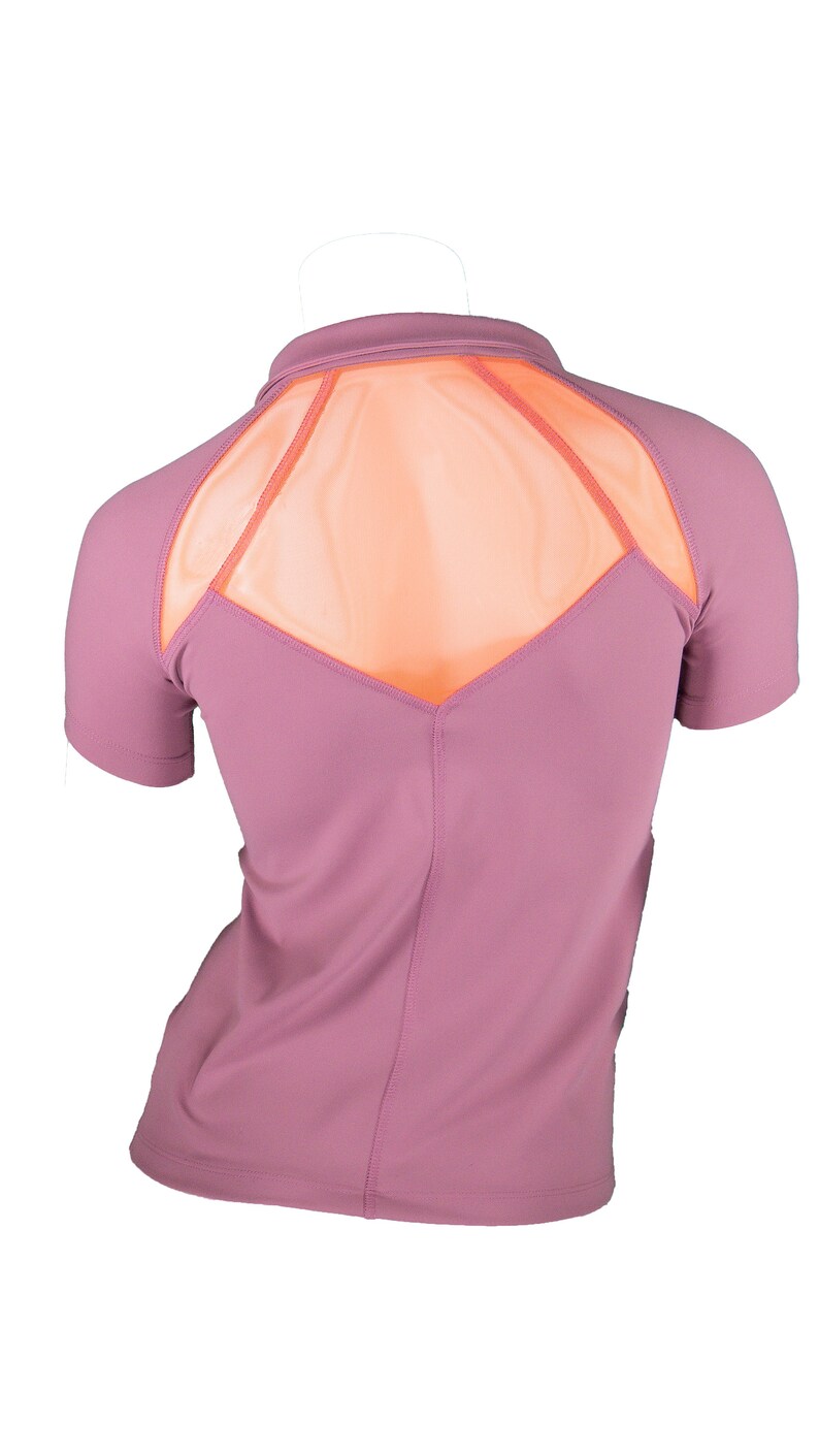 Pode incluir: Uma camisa de manga curta malva com um painel de malha nas costas. O painel de malha &eacute; cor de p&ecirc;ssego e tem a forma de um diamante.