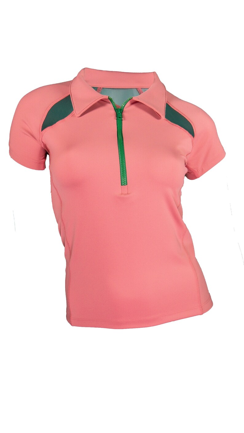 Pode incluir: Uma camisa rosa de manga curta com um z&iacute;per verde e pain&eacute;is de malha verde escura nos ombros.