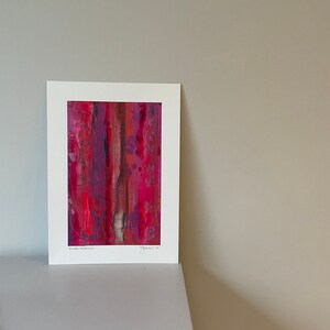 May include: Abstract art print in shades of red, pink, and purple. The print is framed in a white mount and has the artist's signature and the year "2018" in the bottom right corner.