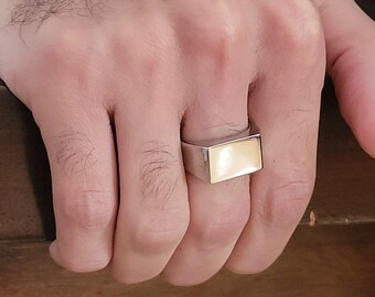 May include: A silver ring with a rectangular, light yellow stone.