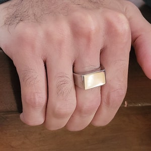 Peut inclure: Une bague en argent avec une pierre rectangulaire de couleur jaune clair.