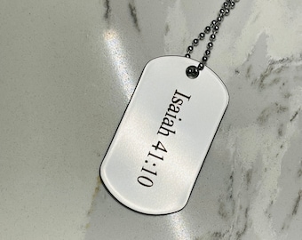 May include: A silver dog tag necklace with a white background and the text "Isaiah 41:10" engraved on it.