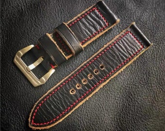 May include: A black leather watch strap with red stitching. The strap has a buckle with a silver finish.