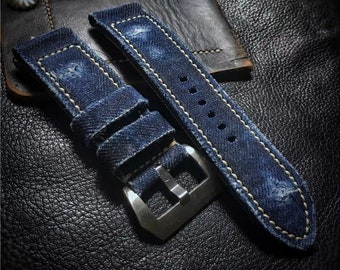 May include: Two blue denim watch straps with white stitching and a silver buckle.