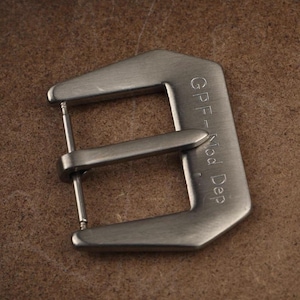 May include: A silver metal watch buckle with the text "GPF - Mod Dep" engraved on the side.